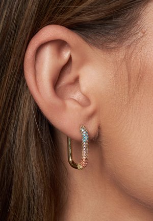 Boucles d'oreilles en forme de créole dorées, ornées de strass multicolores dans un motif dégradé, avec une surface lisse et une finition brillante.