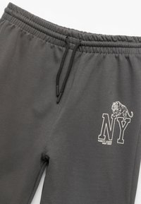 Mørkegrå sweatpants med elastisk talje og snor. Har et hvidt trykt "NY" logo og et tiger grafik. Blød tekstur.