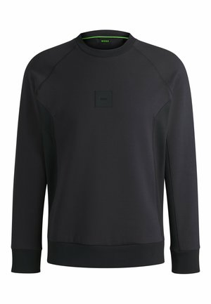 Svart sweatshirt gjort av mjukt tyg, med rund hals, raglanärmar och en texturerad patch med logotyp på framsidan.