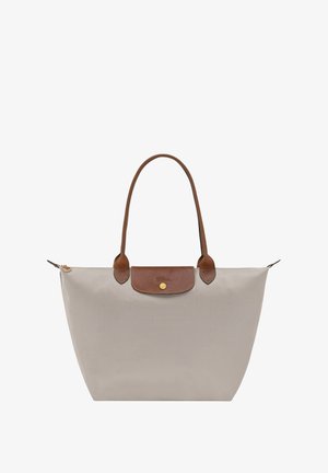 Beige Tragetasche aus Nylon mit braunen Lederakzenten und Griffen, ausgestattet mit einem goldenen Knopfverschluss und einer strukturierten Form.