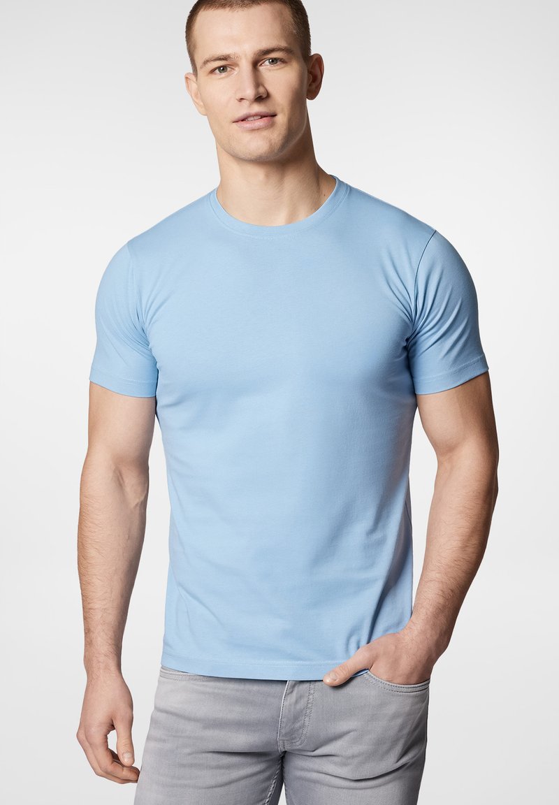 Jasnoniebieska koszulka z krótkim rękawem wykonana z miękkiej mieszanki bawełny, z okrągłym dekoltem i dopasowanym krojem, w komplecie z jasnoszarymi spodniami.