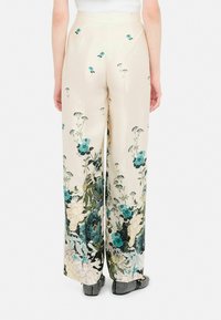 Pantaloni a gamba larga in satin crema, con motivi floreali verdi e blu. Vita alta, linee pulite e una leggera lucentezza.