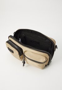Borsa beige con dettagli neri, dotata di un ampio scomparto principale con zip, due tasche frontali con zip e interno in tessuto testurizzato per una migliore organizzazione.