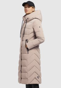 Beige gepolsterter langer Mantel mit Zickzackmuster, abnehmbarem Kapuze, Kordelzügen und seitlichen Reißverschlusstaschen. Schwarzes Logo-Detail ist sichtbar.