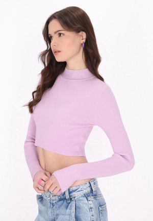 Top lungo a maniche lunghe a coste di colore viola chiaro con colletto alto. Design aderente abbinato a pantaloni denim a vita alta di colore blu chiaro.