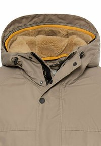Beige isolierte Jacke mit einem fellgefütterten Kapuzen, ausgestattet mit gelben Akzenten, einem Reißverschluss vorne und Druckknöpfen, aus einem glatten Stoffmaterial.