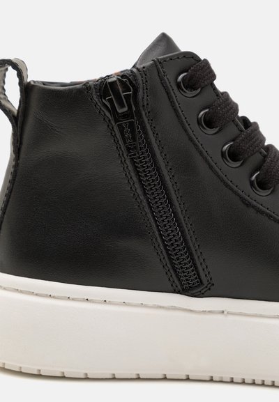 Baskets montantes en cuir noir avec une semelle en caoutchouc blanc, dotées de lacets noirs et d'une fermeture éclair sur le côté. Texture lisse avec des détails de coutures subtils.
