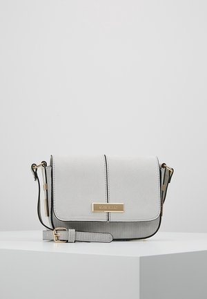 Sac bandoulière gris clair avec sangle réglable, bordure noire, boucle dorée et plaque rectangulaire dorée avec nom sur le rabat avant.