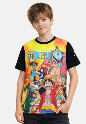 Boy with light brown hair wearing a colorful One Piece anime t-shirt featuring multiple characters against a yellow and orange background.