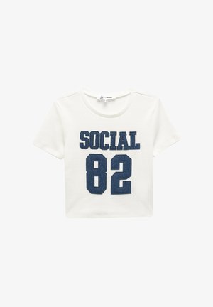 Camiseta blanca de manga corta con la palabra "SOCIAL" y el número "82" impresos en azul oscuro en el frente. Hecha de algodón suave con una textura acanalada.
