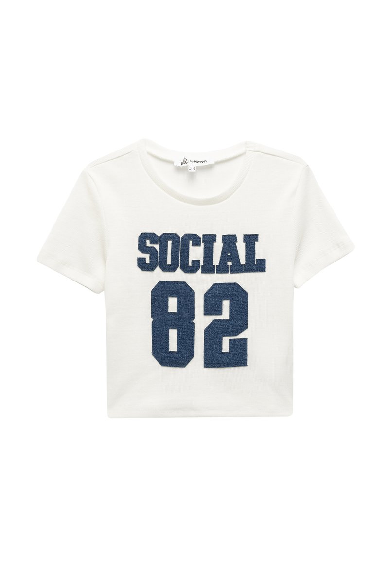 Camiseta blanca de manga corta con la palabra "SOCIAL" y el número "82" impresos en azul oscuro en el frente. Hecha de algodón suave con una textura acanalada.