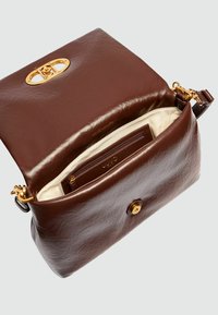 Bruine leren handtas met een gestructureerde afwerking, gouden accenten en een logo-detail. Het interieur heeft een crèmekleurige voering en een ritsvak.