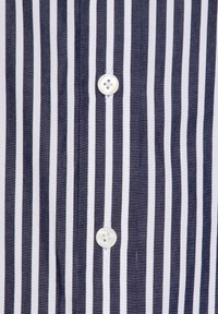Gestreept overhemd met marineblauwe en witte verticale strepen, twee ronde witte knopen en een gladde stoftextuur met nette stiksels.