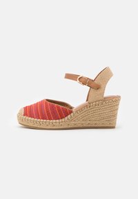 Rote und lila gestreifte Wedgesandalen mit einer geflochtenen Jutesohle, einem Lederknöchelriemen und einem Schnallenverschluss, die über ein geschlossenes Zehendesign verfügen.