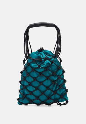 Sac à poignée en filet noir contenant une pochette en satin bleu sarcelle brillant avec cordon, sur un fond clair uni.