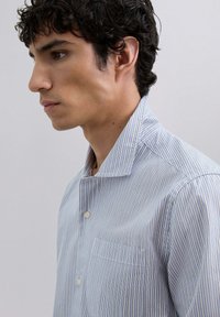 Camisa de botones a rayas azul y blanca con una textura suave, cuello puntiagudo, bolsillo en el pecho y mangas cortas.