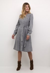 Grey denim dress with long puff sleeves, a button-down front, and a tie belt at the waist. Mid-length skirt, subtle fading, and stitching details.