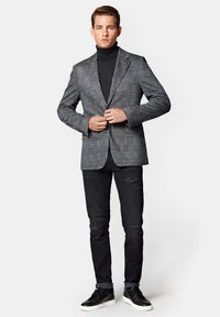 Szary w kratę żakiet na czarnym golfie, zestawiony z podartymi czarnymi dżinsami i czarnymi trampkami, charakteryzujący się eleganckim krojem i dopasowanym fasonem.