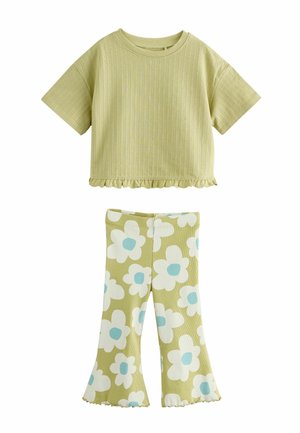 Top cu mâneci scurte, verde deschis, din material reiat, cu tiv cu volănașe și pantaloni evazați asortați cu imprimeuri mari florale albe și albastre.