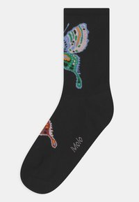 Meias pretas com um design de borboleta multicolorida, apresentando detalhes em azul, verde, laranja e vermelho. O texto "Molo" aparece perto do dedo do pé.