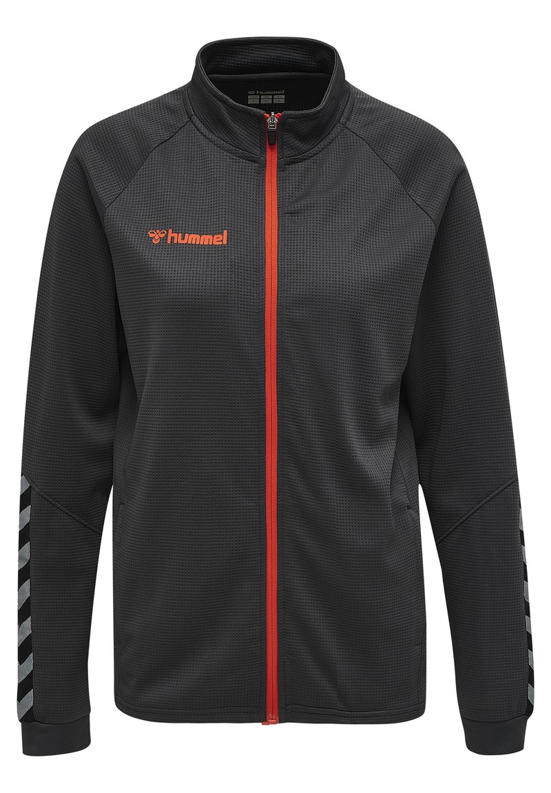 Veste noire zippée en tissu texturé, dotée d'une fermeture éclair orange et d'un logo. Agrémentée de rayures en chevron grises sur les manches.