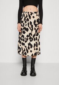 Falda midi de estampado de leopardo en beige y negro, con una textura suave, cinturilla alta y un par de botas negras hasta el tobillo.