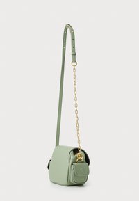 Sac à bandoulière en cuir vert avec une finition texturée, présentant un accent en chaîne dorée, une sangle réglable et une petite poche avant.