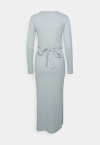 Vestido de manga longa, azul claro, com nervuras, com um laço na cintura e uma abertura lateral. Textura suave e design ajustado.