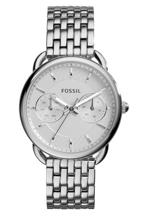 Montre-bracelet Fossil argentée avec bracelet à maillons métalliques, cadran rond blanc affichant l'heure, le jour de la semaine et les sous-cadrans des secondes, avec des index et aiguilles argentés.