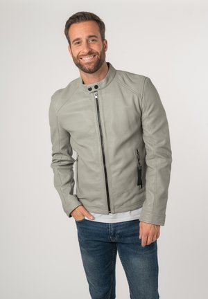 Veste en cuir grise avec un col montant, fermeture éclair à l'avant et poches latérales. Finition texturée avec des accents de fermeture éclair noirs contrastants.