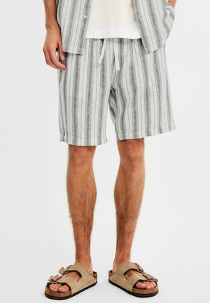 Leinenmischung Shorts in Hellgrau mit vertikalen schwarzen Streifen, ausgestattet mit einem elastischen Bund und Kordelzug, kombiniert mit beigen Sandalen.