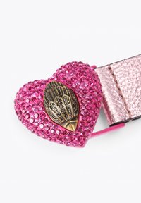 Roze hartvormige riemgesp bedekt met strass-steentjes, met een bronzen bladontwerp in het midden. De riem is metallic roze.