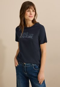 Camiseta de color azul marino con mangas cortas, que presenta el texto "PIÙ AMORE" en un contorno azul claro en el pecho. Tejido suave, corte relajado.
