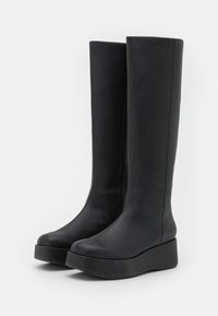 Botas de cuero negras hasta la rodilla con un diseño elegante, punta redondeada y suela con plataforma. Cremallera lateral para poner y quitar fácilmente. Textura suave.