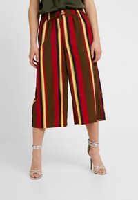 Široké kalhoty culottes s vertikálními červenými, žlutými a modrými pruhy na hnědém pozadí; elastický pas; hladký materiál; délka do poloviny lýtek.