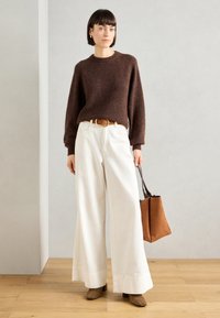 Καφέ πουλόβερ από μάλλινο ύφασμα, φαρδύς λευκός παντελόνι, καφέ ζώνη, καφέ τσάντα, μπεζ μποτάκια με τακούνι, υφασμάτινη υφή, άνετη εφαρμογή, μινιμαλιστικός σχεδιασμός.