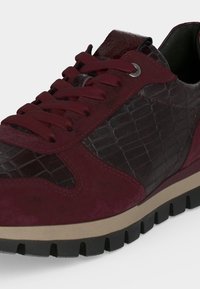 Baskets bordeaux avec panneaux latéraux texturés foncés, surpiqûres en daim, semelle intermédiaire épaisse beige, semelle extérieure noire rugueuse et lacets bordeaux assortis.