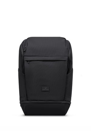 Black rectangular backpack with front zip pocket and side pockets, featuring a small brand logo patch on the front center.
