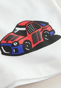 Voiture de course de dessin animé rouge et bleue avec des détails noirs et le numéro 01 sur le côté, imprimée sur un tissu blanc.