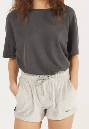 T-shirt oversize gris charbon à manches courtes associé à un short gris clair avec cordon de serrage, affichant un slogan brodé et des poches.