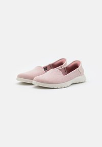 Zapatos tipo slip-on en suave tela rosa con un patrón texturizado, suela de goma blanca y paneles laterales elásticos para facilitar su uso.