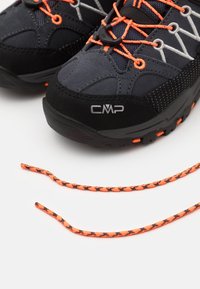 Black and gray hiking shoes with orange accents, featuring a textured surface and contrasting shoelaces. CMP logo visible on the side.