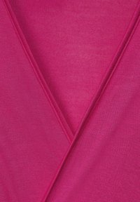 Närbild av rosa tyg med synliga diagonala sömmar och finstickad textur.