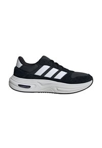 Baskets Adidas noir et blanc avec une semelle blanche épaisse et rembourrée, trois bandes blanches sur le côté, et étiquette "Cloudfoam" sur la semelle du talon.