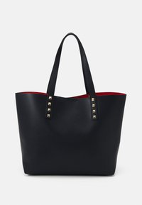 Sac fourre-tout noir avec deux poignées plates, accents en clous dorés et un intérieur rouge vif. Fabriqué en matériau lisse et texturé. Design à ouverture supérieure.