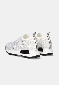 Zapatillas blancas sin cordones con parte superior texturizada que presenta cristales de imitación, acentos negros en la suela y una pestaña con detalle del logo en la parte trasera.