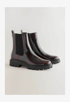 Chunky bordo čizme do članka s sjajnom završnom obradom, elastičnim bočnim panelima i robusnim crnim potplatom. Imaju petne trakice za jednostavno obuvanje.