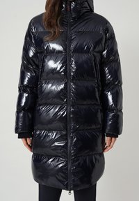 Abrigo acolchado azul marino hecho de material brillante y acolchado con capucha, que presenta un diseño largo y cuadrado y un cierre frontal con cremallera.