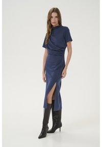 Navy blue dress with short sleeves, draped bodice, and side slit. Paired with knee-high black heeled boots, featuring pointed toes and sleek texture.