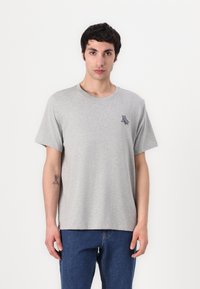 Tricou gri din bumbac, cu guler rotund și mâneci scurte, având un mic design al logo-ului bleumarin în partea stângă a pieptului. Croială clasică.